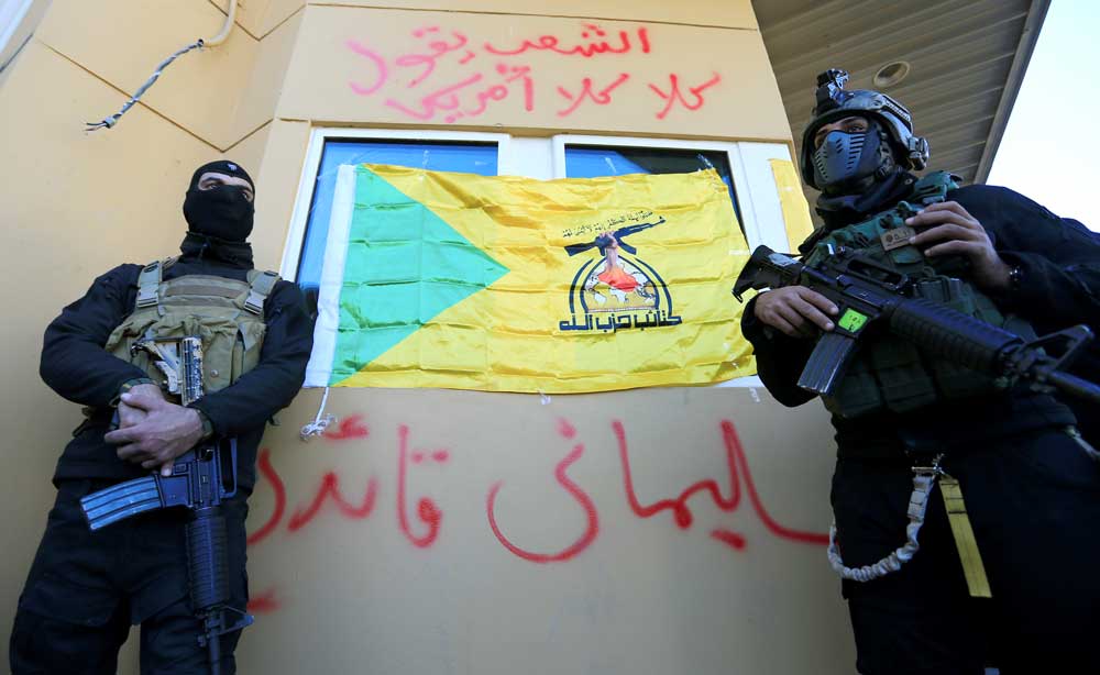 نیروهای امنیتی عراقی از ساختمان سفارت آمریکا محافظت می‌کنند؛ روی دیوار نوشته شده: سلیمانی رهبر! و مردم به آمریکاییان نه می‌گویند؛ بغداد؛ ۳۱ ژانویه ۲۰۱۹