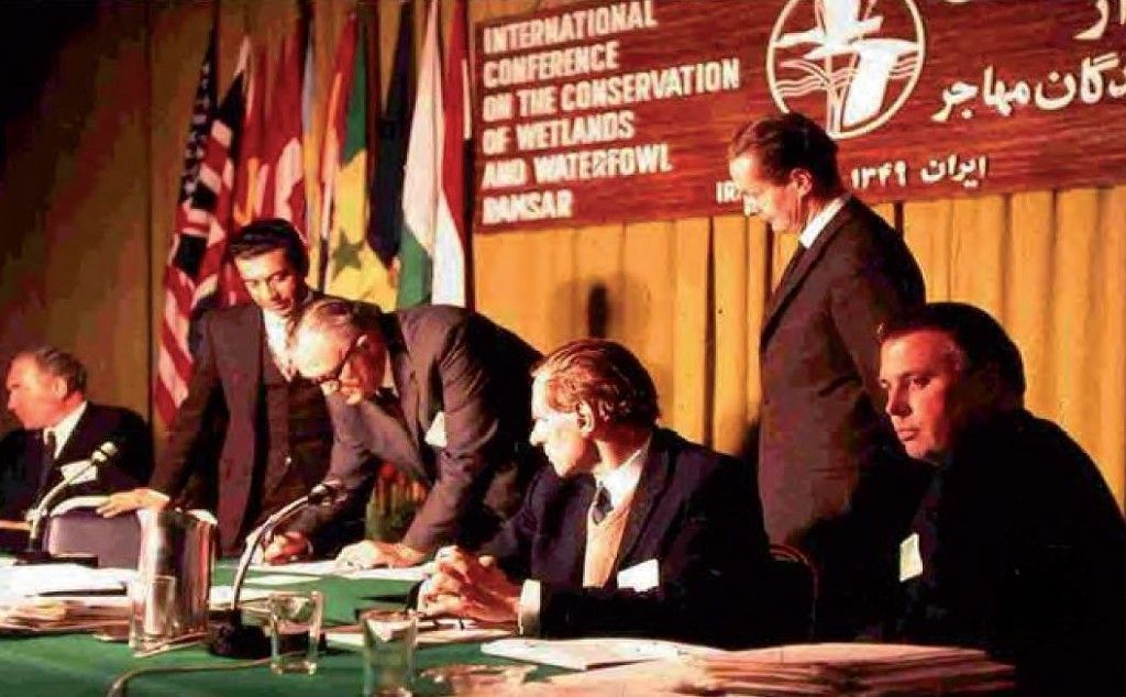 کنفرانس رامسر؛ اسکندر فیروز، رئیس سازمان حفاظت محیط زیست ایران (نفر اول ایستاده سمت چپ تصویر) در کنار نماینده آفریقای جنوبی که سند را امضا می‌کند
